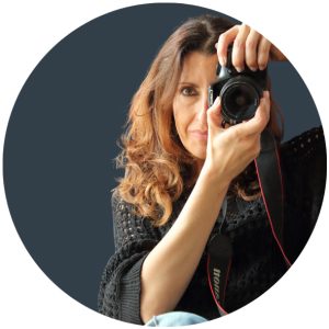 La fotografia di Paola Uberti, creativa digitale del settore enogastronomico, ritratta con una reflex in mano come se scattasse una foto all'osservatore.