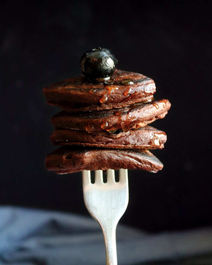 Pancakes al cacao impilati su una forchetta con mirtillo fresco – food photography di Paola Uberti per Vignoli.